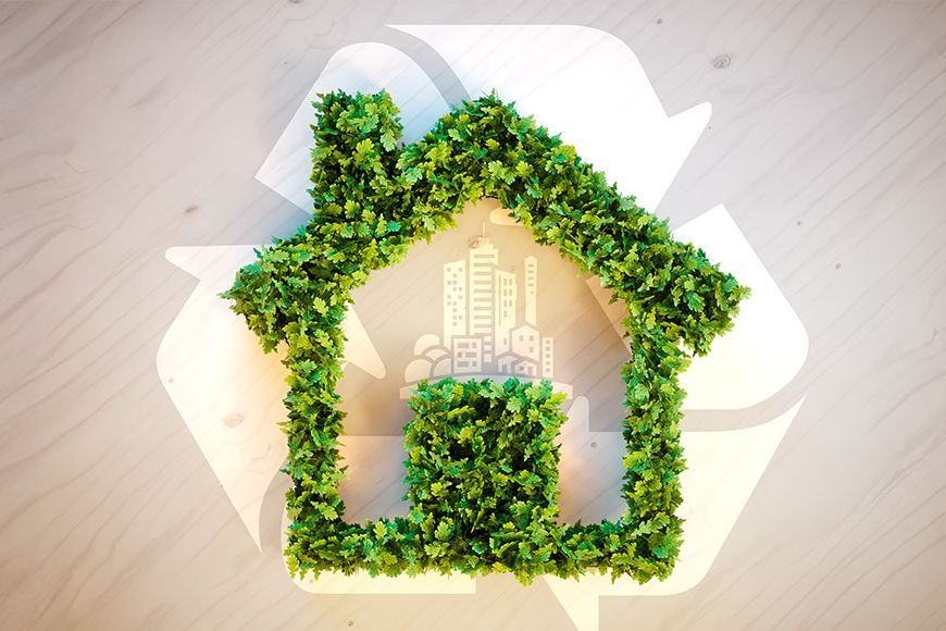 A house shaped in green leaves with a recycle logo in the background